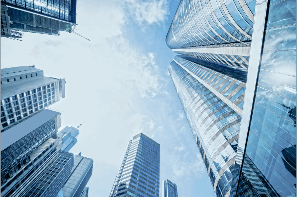 Upward view of modern skyscrapers with reflective glass facades against a blue sky with clouds