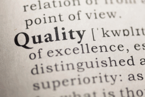 Close-up of the word "Quality" in a dictionary with its definition partially visible.
