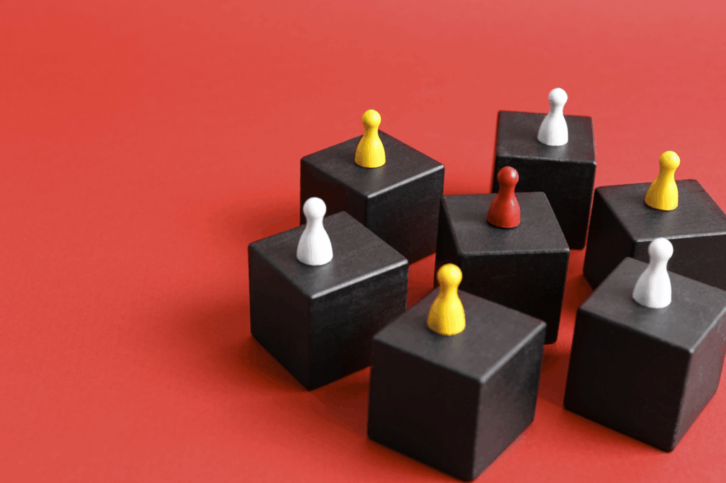 Colorful game pawns on top of black cubes arranged on a red background.