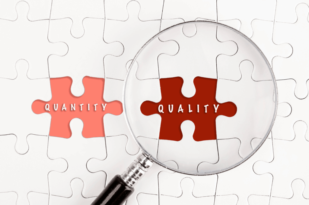 Magnifying glass focusing on a puzzle piece labeled "QUALITY" next to another piece labelled "QUANTITY."