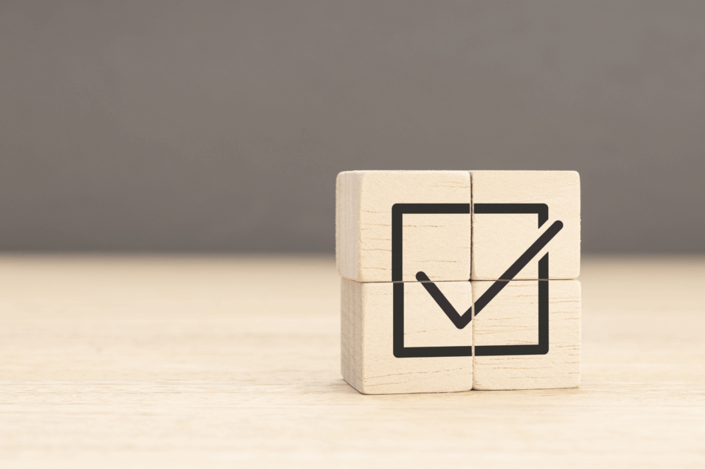 Wooden blocks forming a checkmark icon symbolising compliance, approval, or completion.